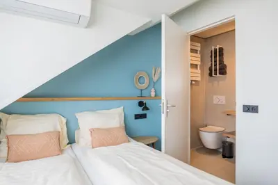 a bedroom with a white bed and a blue wall at Huis 8 Studio's in Katwijk aan Zee