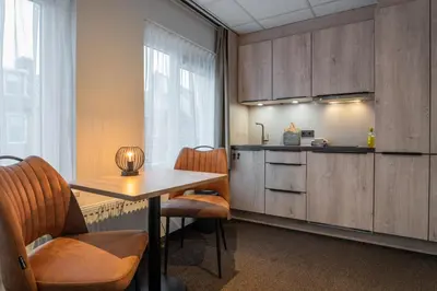 a room with a table and chairs and a kitchen at Huis 8 Studio's in Katwijk aan Zee