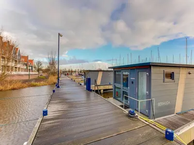 a dock with a building on the side of a river at Houseboat in Volendam near Fort Edam in Volendam