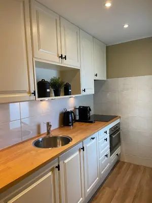 a kitchen with white cabinets and a sink at Apartment Malisa in Zandvoort