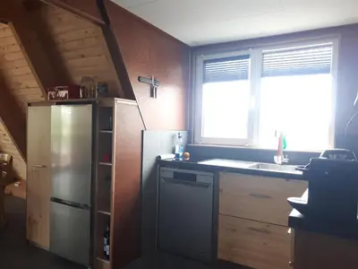 a kitchen with a refrigerator and a sink and a window at A-frame volledig vrijstaande woning in Hensbroek