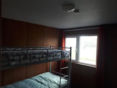 a room with two bunk beds and a window at A-frame volledig vrijstaande woning in Hensbroek