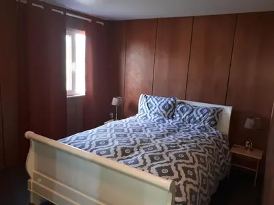a bedroom with a bed with a blue and white comforter and a window at A-frame volledig vrijstaande woning in Hensbroek