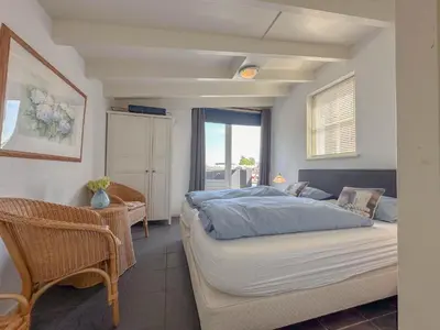 a bedroom with a bed and a chair and a window at Zwaan 24-7 in Breukelen