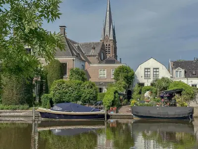 two boats are docked in the water in front of a church at Zwaan 24-7 in Breukelen