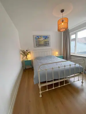 a bedroom with a bed and a large window at Tussen Tulp & Zee in Noordwijk