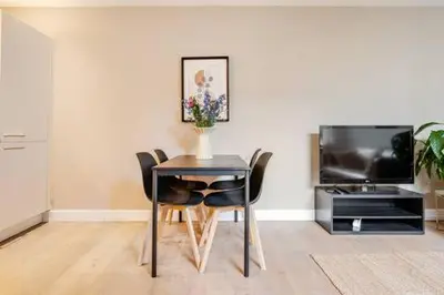 a dining room table with chairs and a television at Tussen Tulp & Zee in Noordwijk