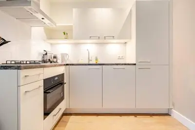 a white kitchen with white cabinets and appliances at Tussen Tulp & Zee in Noordwijk
