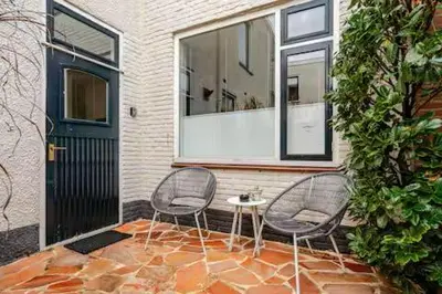 two chairs and a table in front of a house at Tussen Tulp & Zee in Noordwijk