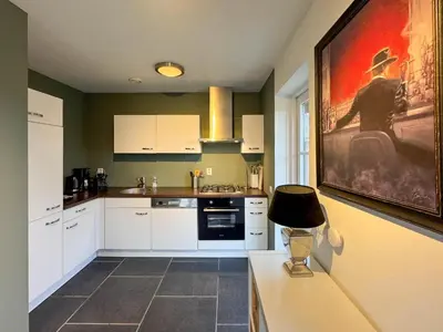 a kitchen with white cabinets and a painting on the wall at Zwaan 24-6 in Breukelen