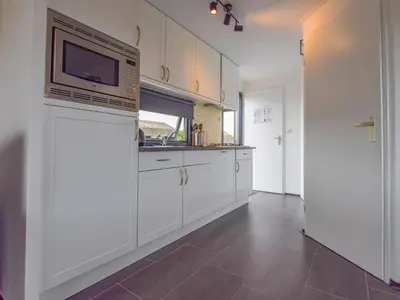a kitchen with white cabinets and a microwave at Blauwborst 24-24 in Breukelen