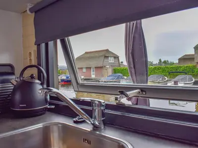a kitchen sink with a view of a house through a window at Blauwborst 24-24 in Breukelen