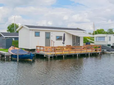 a house on a dock with a boat on the water at Blauwborst 24-24 in Breukelen
