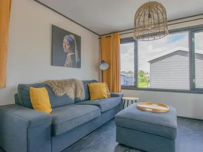 a living room with a blue couch and yellow pillows at Blauwborst 24-20 in Breukelen