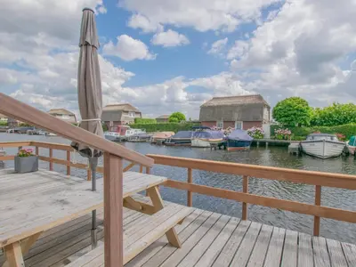a deck with an umbrella and boats in the water at Blauwborst 24-20 in Breukelen