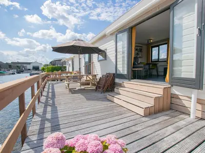 a wooden deck with an umbrella and some flowers at Blauwborst 24-20 in Breukelen