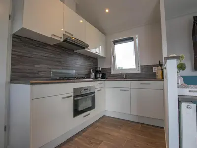 a kitchen with white cabinets and a brick wall at Purperreiger 24-34 in Breukelen