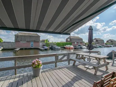 a deck with a table and an umbrella and water at Purperreiger 24-34 in Breukelen