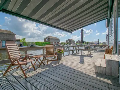 a deck with chairs and tables on the water at Purperreiger 24-32 in Breukelen