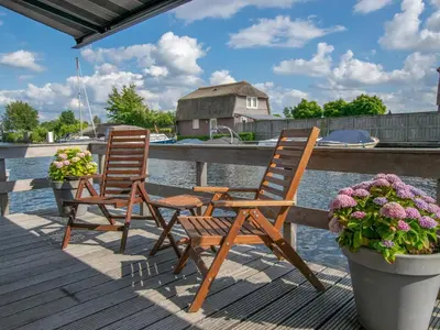 two chairs sitting on a dock near the water at Purperreiger 24-32 in Breukelen