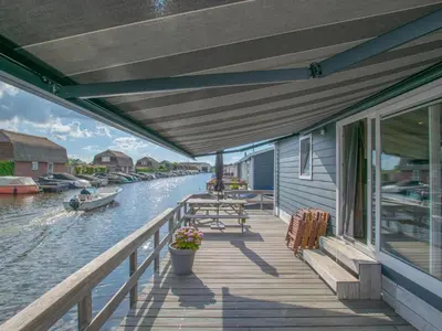 a porch of a house with a boat on the water at Purperreiger 24-32 in Breukelen