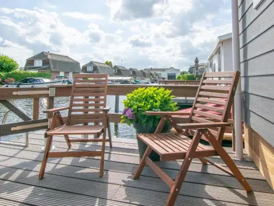 two chairs sitting on a porch with a table and flowers at Grote Karekiet 24-22 in Breukelen