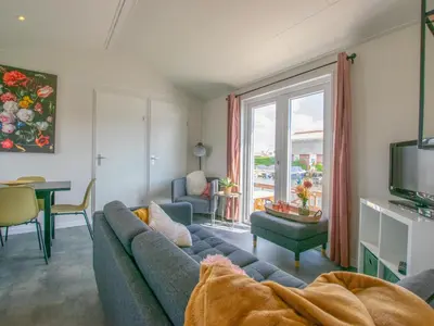 a living room with a blue couch and a tv at Grote Karekiet 24-22 in Breukelen