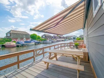 a wooden deck with a picnic bench on the water at Grote Karekiet 24-30 in Breukelen