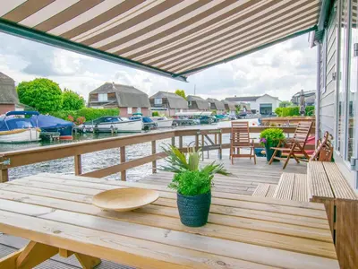 a wooden table on a dock with boats in the water at Grote Karekiet 24-30 in Breukelen
