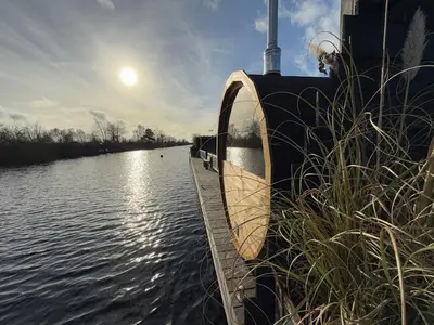 a boat on a river with the sun in the sky at NEW - Private Residence with Sauna - on a lake near Amsterdam in Vinkeveen