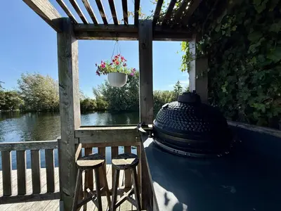 a porch with two stools and a pot with flowers at NEW - Private Residence with Sauna - on a lake near Amsterdam in Vinkeveen