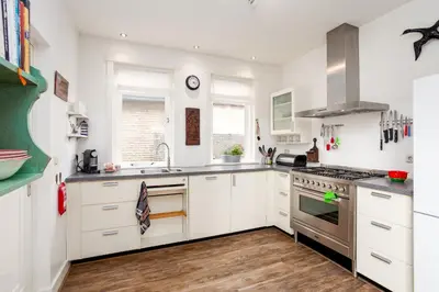 a kitchen with white cabinets and stainless steel appliances at Vakantiehuis Zeevonk in Bergen aan Zee