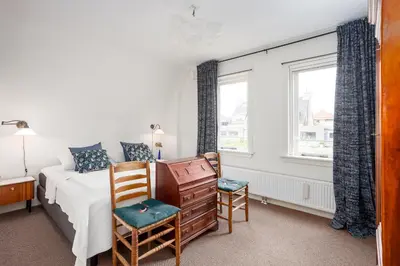 a bedroom with a bed and two chairs at Vakantiehuis Zeevonk in Bergen aan Zee