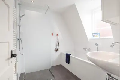 a white bathroom with a shower and a sink at Vakantiehuis Zeevonk in Bergen aan Zee