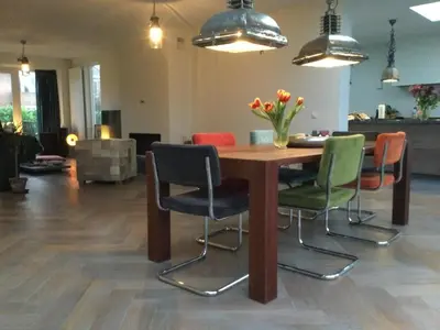 a wooden table with chairs and a vase of flowers at Villa Cosy Central incl Jacuzzi Near trainstation, beach and city in Heemstede