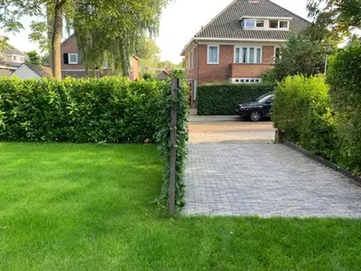a fence in front of a house with a driveway at Villa Cosy Central incl Jacuzzi Near trainstation, beach and city in Heemstede
