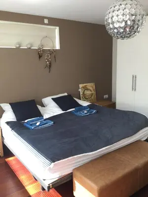 a bedroom with a large bed with a blue blanket at Villa Cosy Central incl Jacuzzi Near trainstation, beach and city in Heemstede