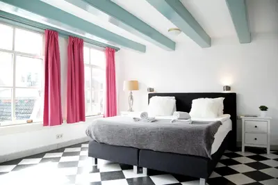 a bedroom with a large bed with red curtains at Modern Canal House Loft - City Center in Amsterdam