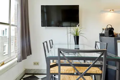 a dining room with a glass table and chairs at Modern Canal House Loft - City Center in Amsterdam
