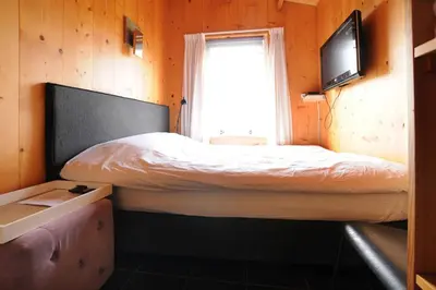 a small bedroom with a bed and a television at Chalet Egmond in Egmond aan den Hoef