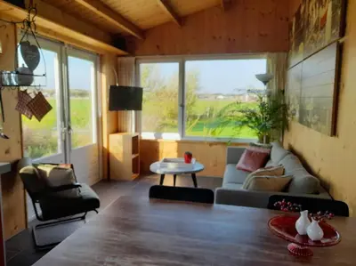 a living room with a couch and a table at Chalet Egmond in Egmond aan den Hoef