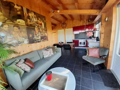 a living room with a couch and a kitchen at Chalet Egmond in Egmond aan den Hoef