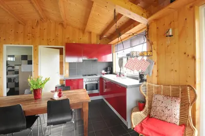 a kitchen with red cabinets and a wooden ceiling at Chalet Egmond in Egmond aan den Hoef