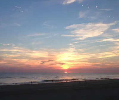 a sunset on a beach with the ocean at De Windroos | Atelier Aan Zee in Groet