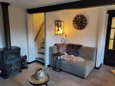 a living room with a couch and a clock on the wall at Luxe vakantiehuisje in prachtige en rustgevende omgeving in Nieuwe-Niedorp