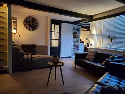 a living room with a couch and a table and a clock at Luxe vakantiehuisje in prachtige en rustgevende omgeving in Nieuwe-Niedorp