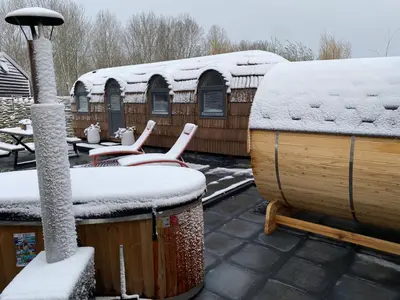 a snow covered rooftop with two chairs and a hot tub at Bed & Wellness Klein Knorrestein with private hottub and sauna and tandembike rental included in price in Almere
