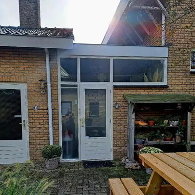 a brick house with a white door and a table at Carmen's Stay In - Jaagweg 13 - Ilpendam - 15 minuten naar Amsterdam met de bus in Ilpendam
