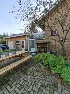 a backyard with a wooden bench and a house at Carmen's Stay In - Jaagweg 13 - Ilpendam - 15 minuten naar Amsterdam met de bus in Ilpendam