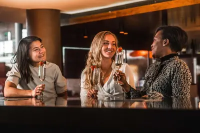 three people sitting at a bar drinking champagne at Hyatt Place Amsterdam Airport in Hoofddorp